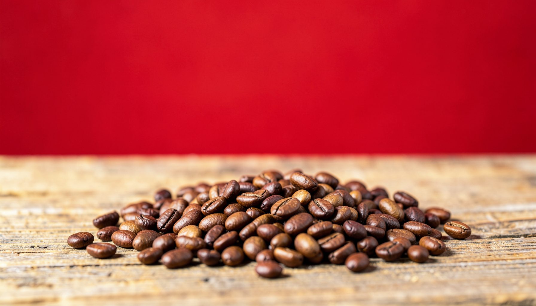Granos de café tostados y semillas de cacao esparcidos sobre una superficie rústica de madera, en tonos marrones cálidos y ocres, iluminación natural suave